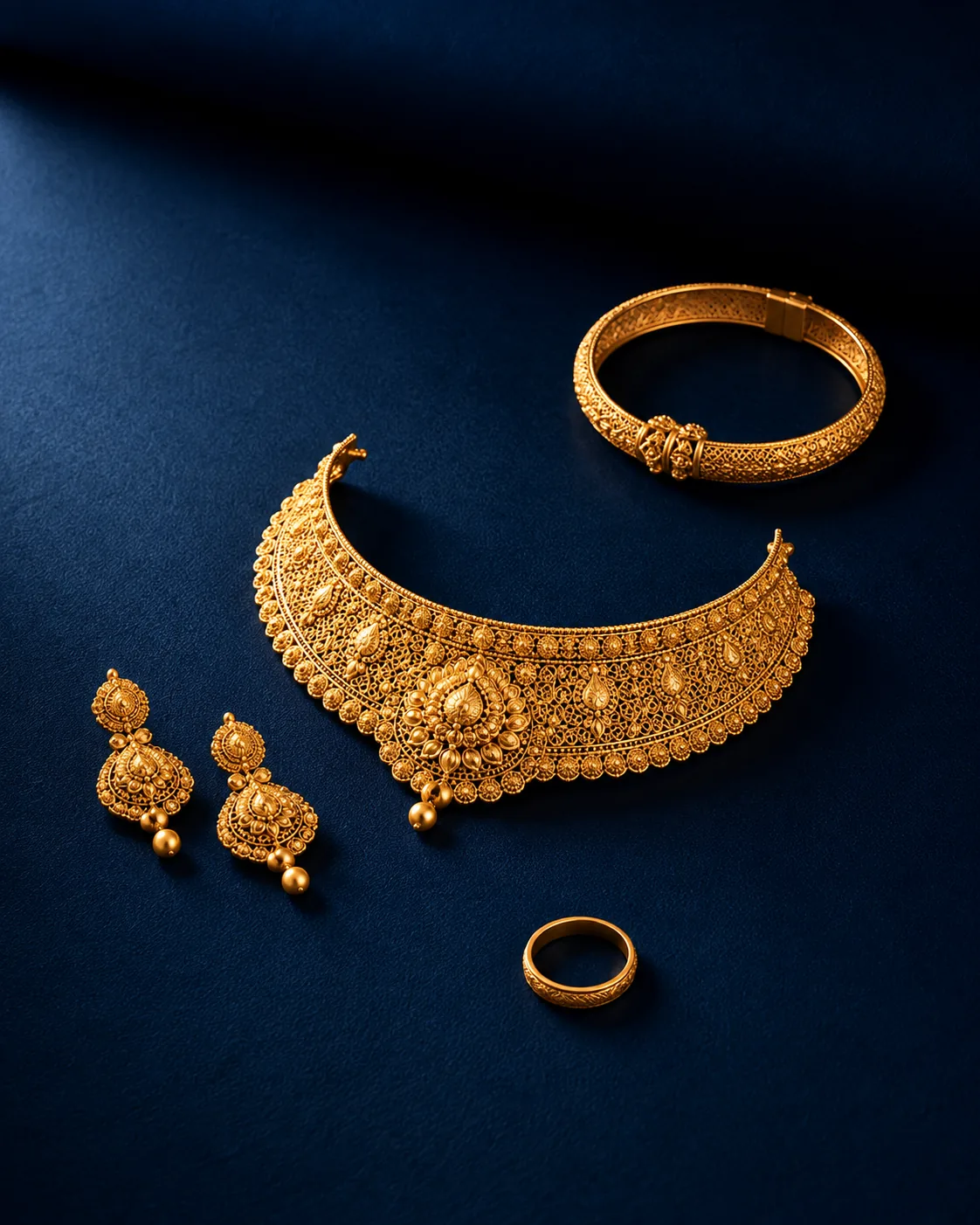 Yellow gold filigree choker with matching earrings, bangle and ring on navy velvet