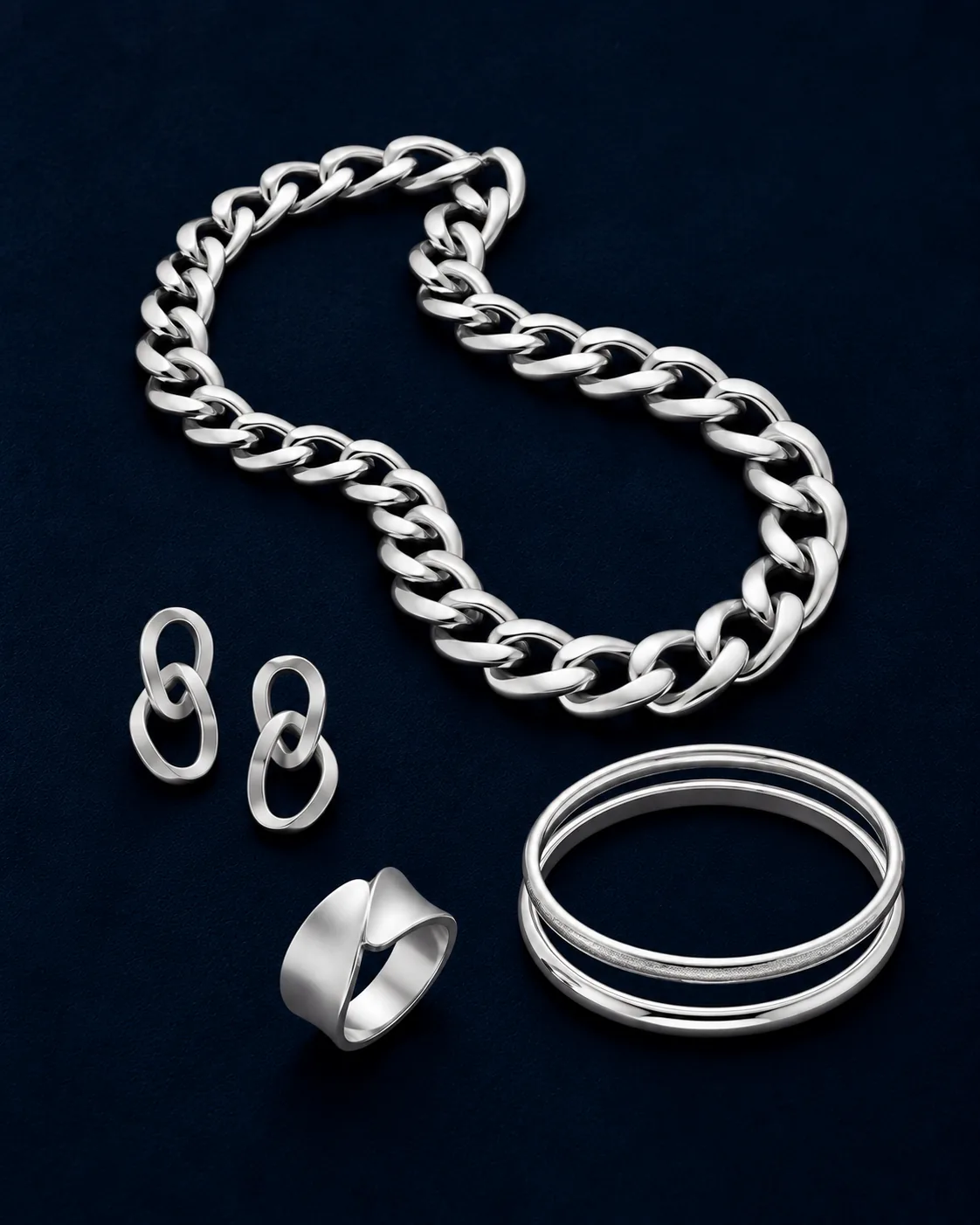 Silver curb chain with link earrings, twin bangles and a ring on navy